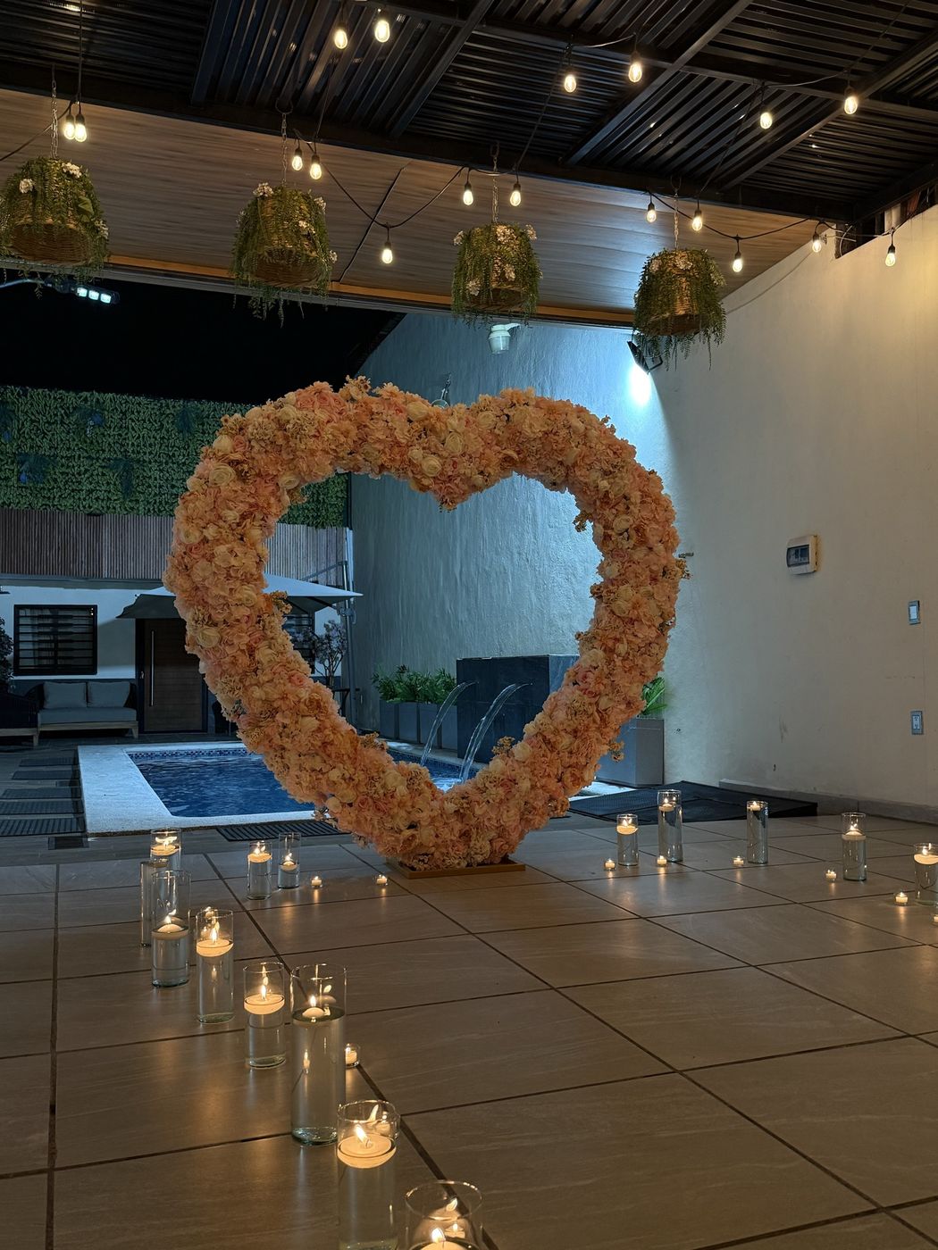 El corazón de flores visto de frente, con la alberca iluminada detrás