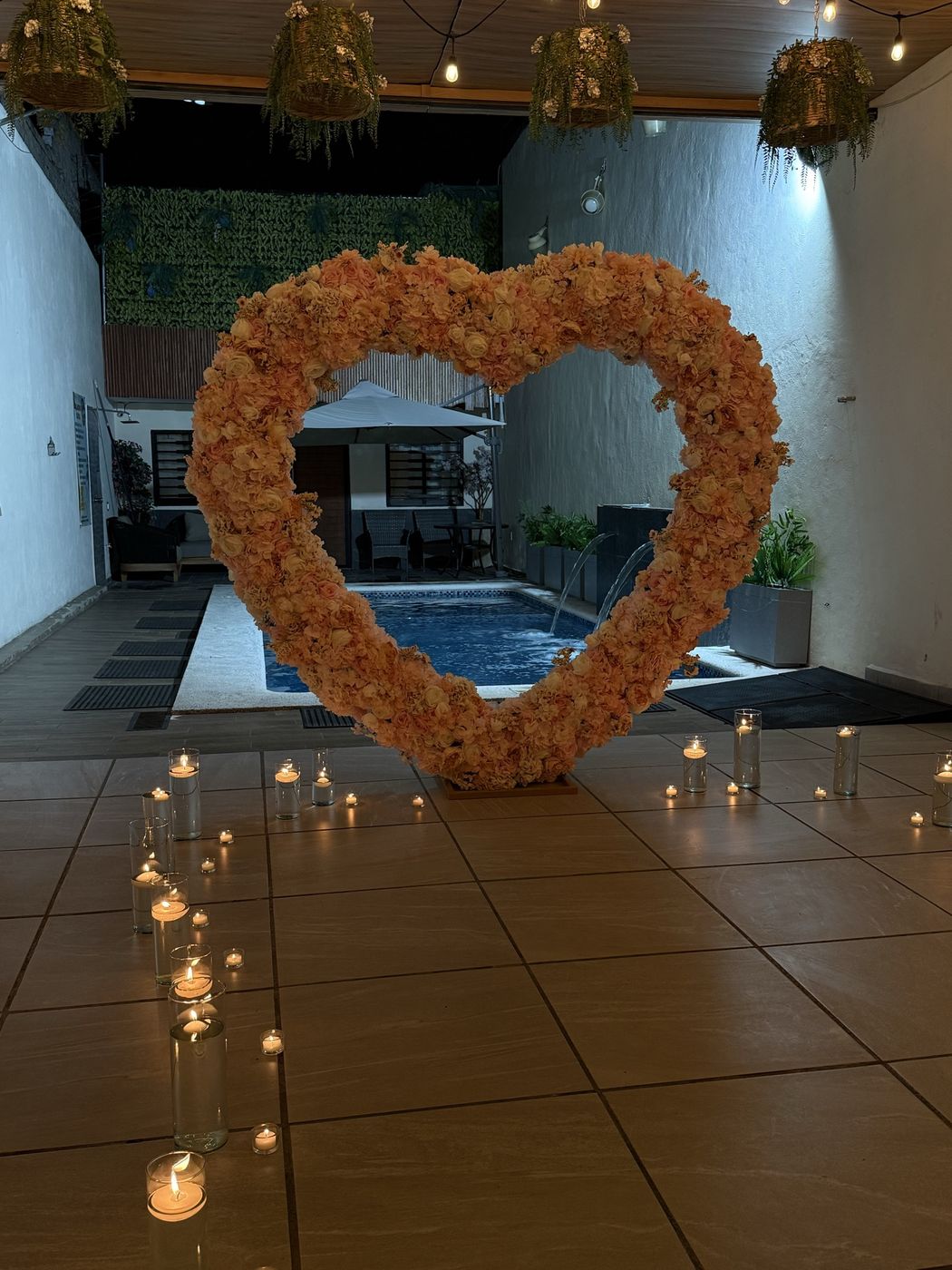 El corazón floral con el camino de velas encendidas hacia la alberca