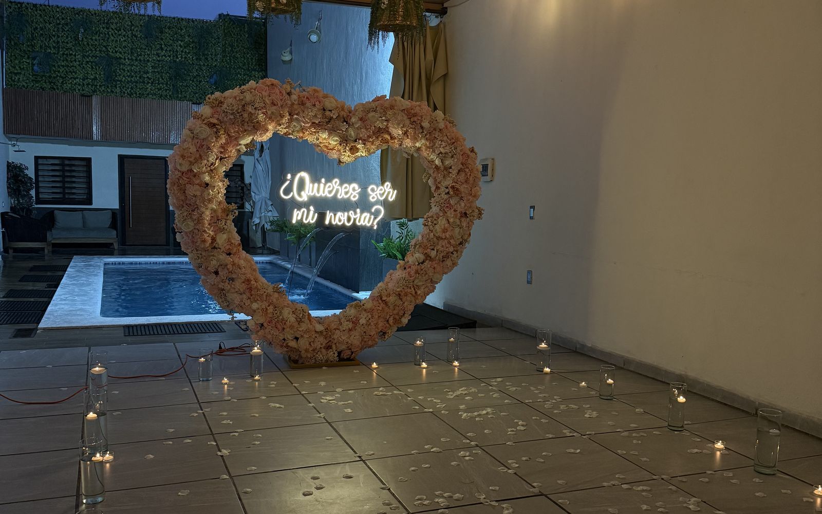 El corazón de flores frente a la alberca iluminada de Terraza Plutarco, con velas encendidas en el piso de la terraza, en Guadalajara